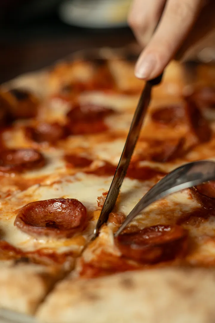 Una pizza al salame piccante tagliata a spicchi, appena uscita dal forno a legna – La Vecchia Rama, Negrar